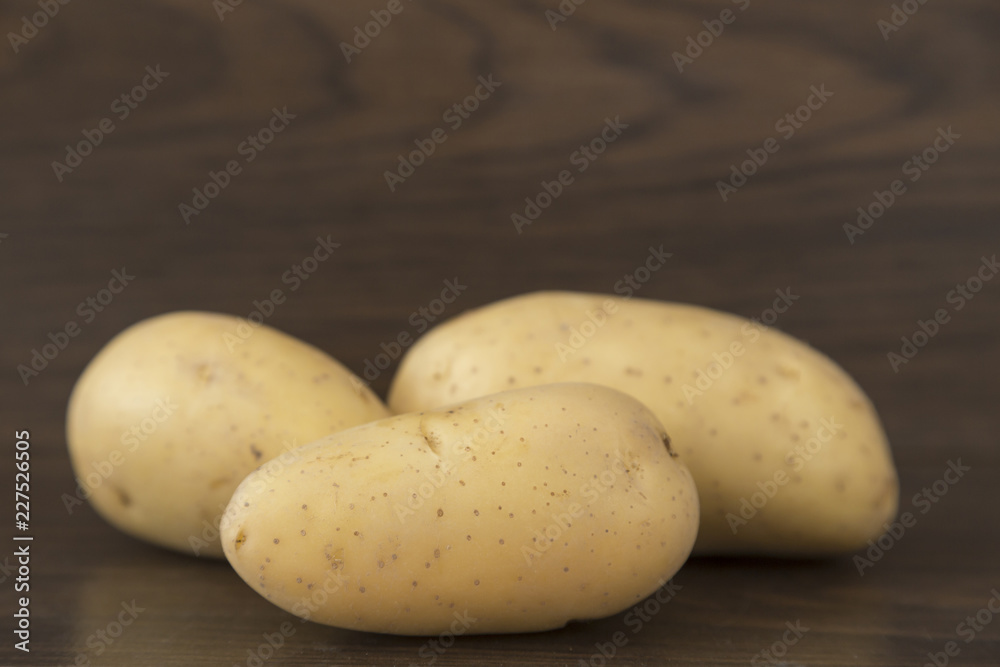 three potatoes on brown background three potatoes on brown background