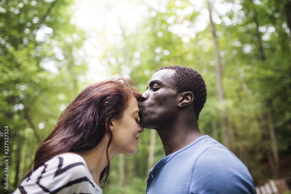 Fototapeta premium Side view of man kissing woman's forehead