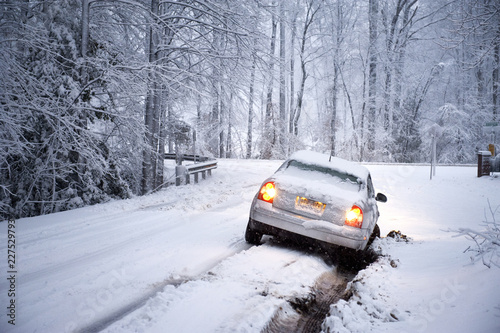 Car stuck in snow covered road against bare trees