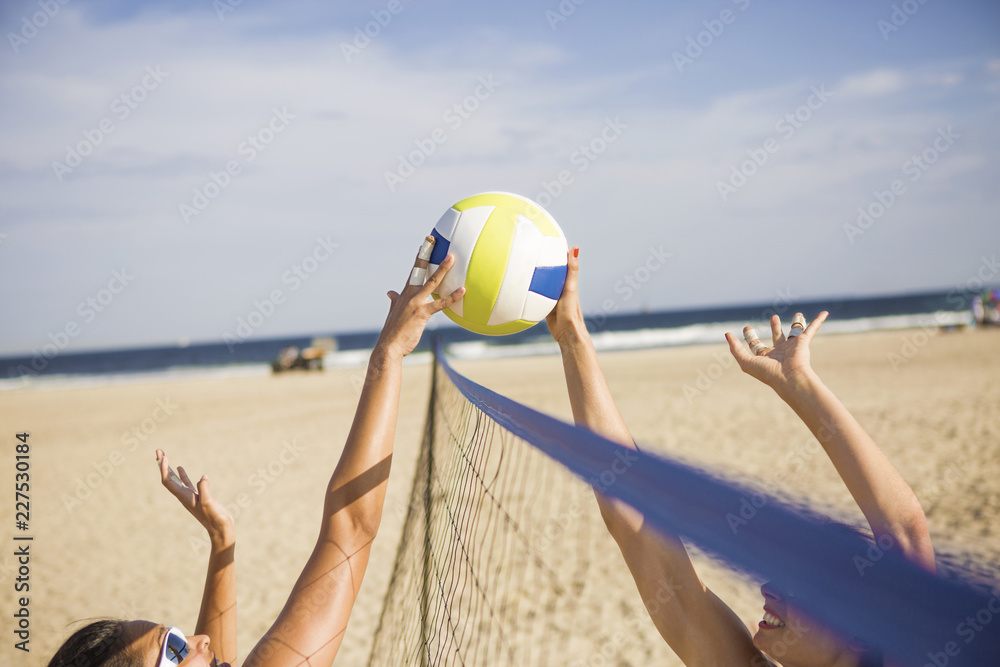 Obraz premium Friends playing beach volleyball on sunny day