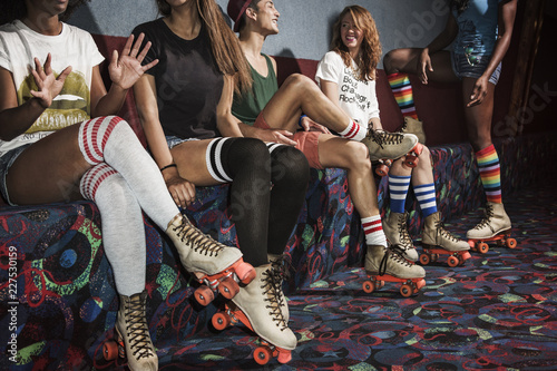 фотографія Friends wearing roller skates sitting on multi colored sofa at roller rink