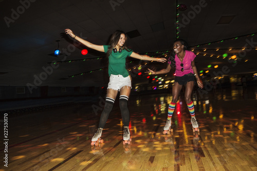 Fotografia Friends enjoying roller skating at illuminated roller rink
