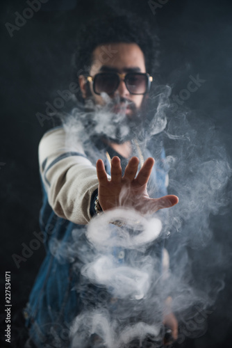 Smoking vape. vaping man holding a mod. Vape Rings. A man launches a ring of smoke. Tricks with smoke.