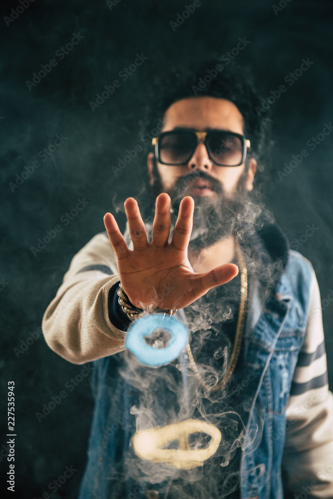 Smoking vape vaping man holding a mod. Vape color rings. A man throws smoke- colored rings. Tricks with smoke. Stock Photo | Adobe Stock