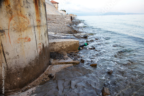 Contaminated water, sewage waste is drained through pipe into sea on an unequipped beach. Pollution of environment, ecological catastrophe. Environmental problem photo