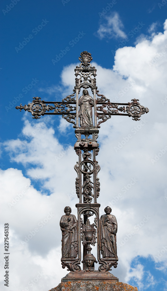 Antique ornate rusty cross at the old cemetery in Provence (France). Jesus (with sacred heart) and apostle Peter (with key) and apostle Paul (with sword). 