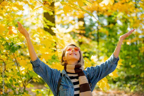 Young beautiful blonde girl in blue jeans clothes have rest in the park in autumn season time.