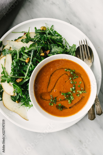 Close up view of tomato soup with pear and arugula salad