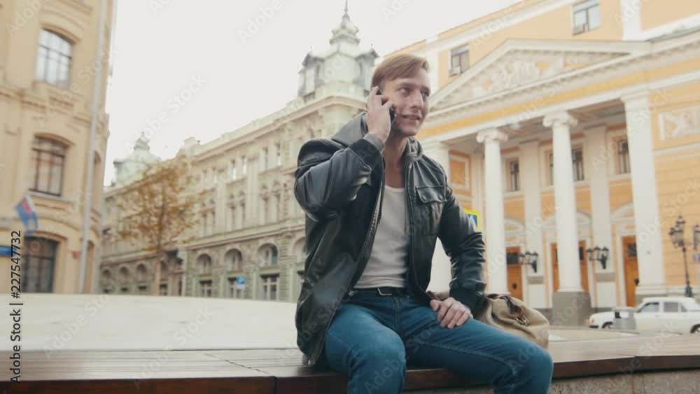 Young brutal man talking on the phone in a European city. Slo-mo Young brutal man talking on the phone in a European city. Slo-mo