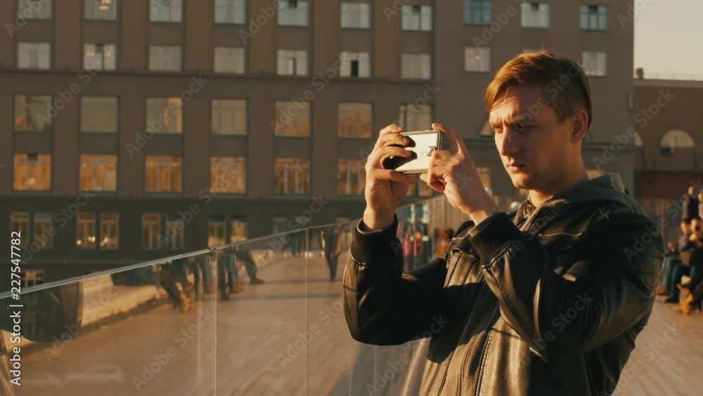 Young brutal man takes photos on a smartphone. Middle shot