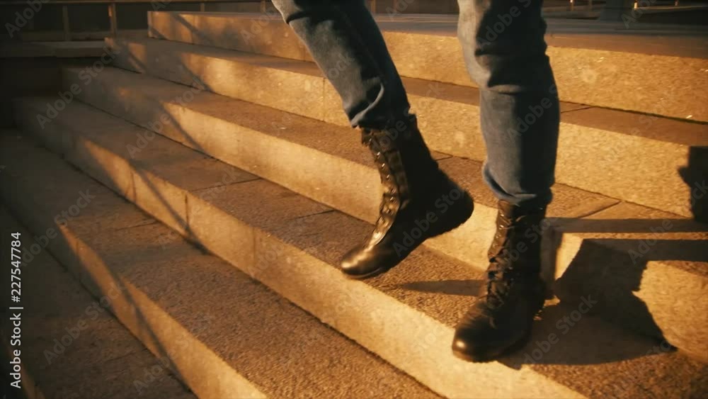 Young brutal man in military boots coming down the stairs. Slo-mo