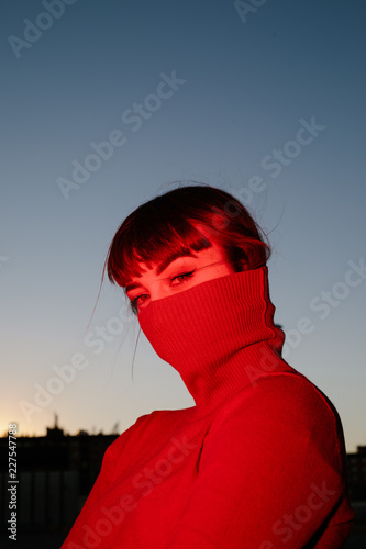 Portrait of young woman in maroon turtleneck covering lower half face