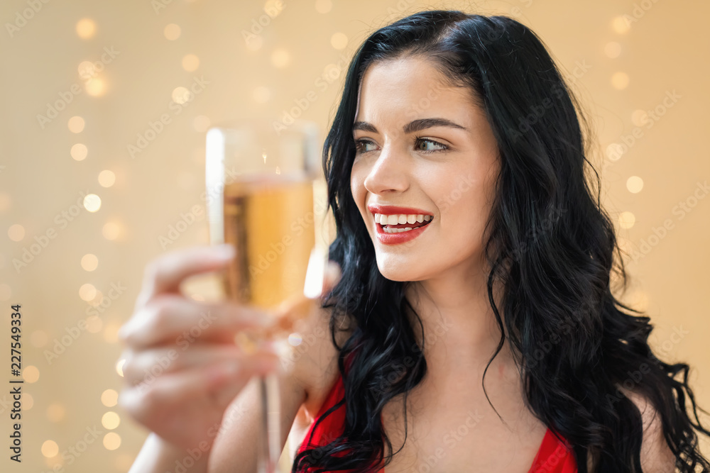 Young woman holding a champagne flute on a shiny light background Young woman holding a champagne flute on a shiny light background