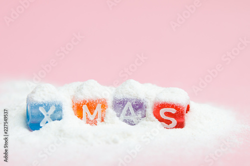 words merry christmas made of colorful letters blocks on white snow and pink background. Flat lay, top view - holidays, winter, christmas and new year celebration concept.