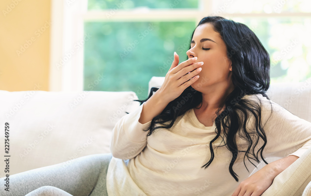 Young woman yawning in a bright interior room Young woman yawning in a bright interior room