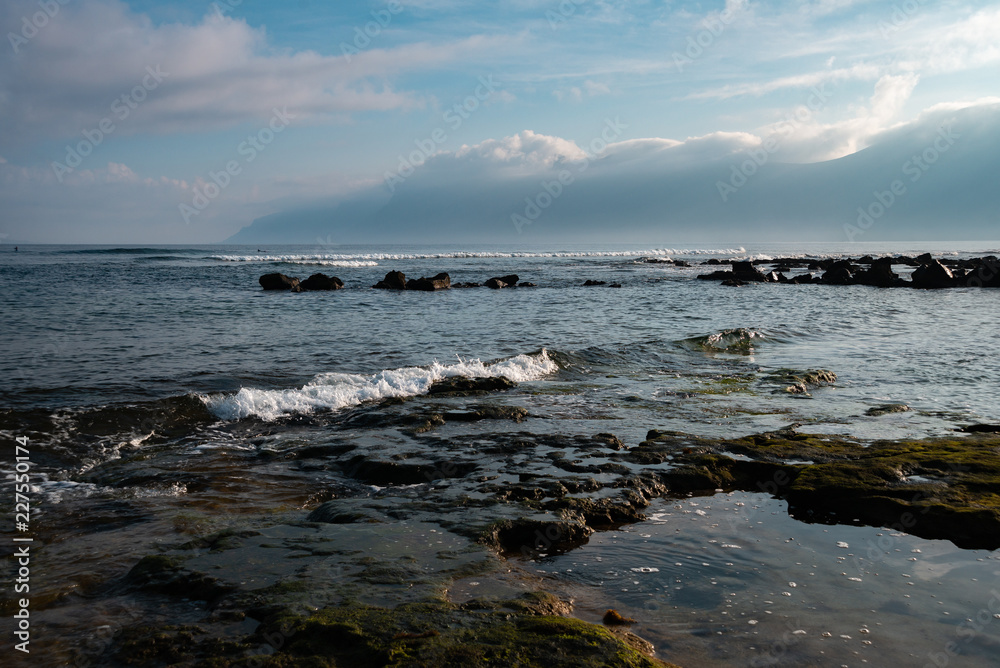 morning on the ocean at low tide, green stones and smooth pools, reflecting the sky