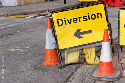 Yellow diversion sign and two road cones in a UK city street