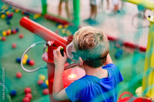 Child playing at a summer fair with a cannon of colored balls of compressed air.