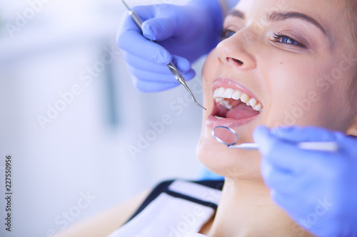 Young Female patient with open mouth examining dental inspection at dentist office.