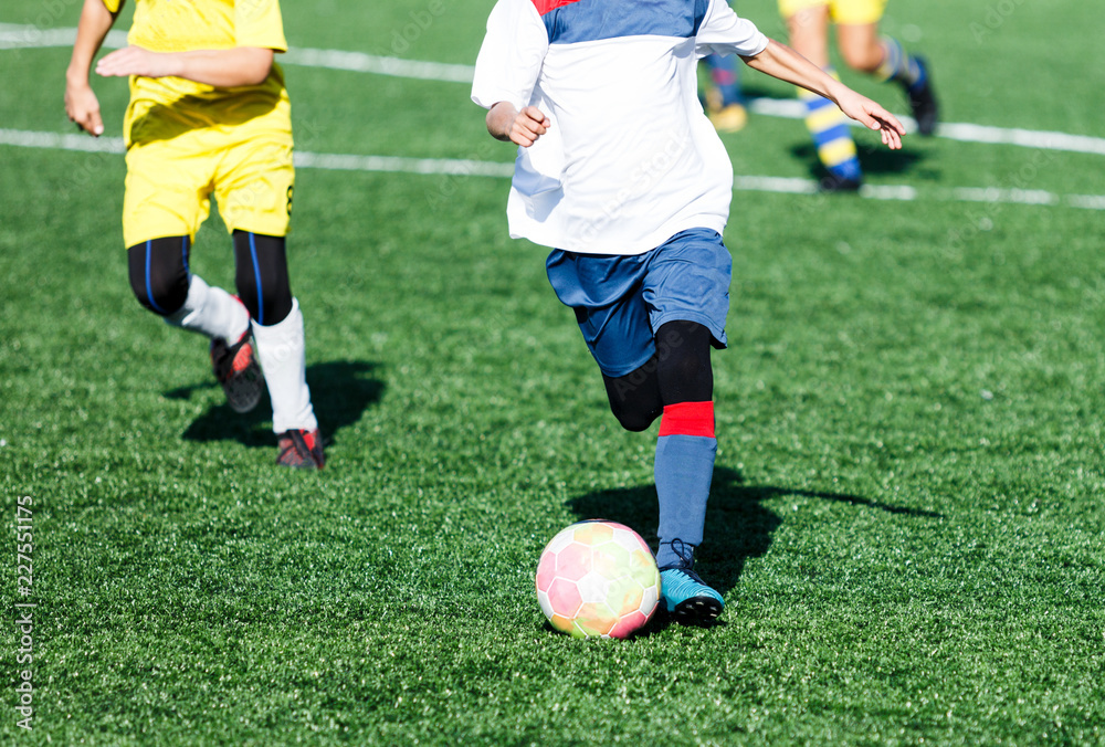 football teams - boys in red, blue, white uniform play soccer on the green field. boys dribbling. dribbling skills. Team game, training, active lifestyle, hobby, sport for kids concept