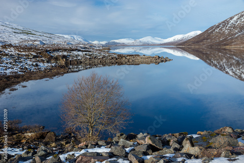 Mountains reflected in icy water in the Scottish Highlands