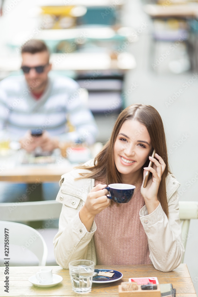 Young beautiful woman in a cafe talking on a phone and smiling