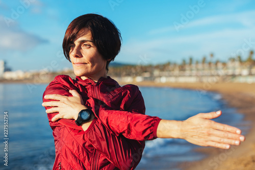 Mature woman stretching by the beach.