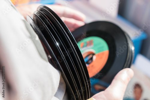 Person sucht aus einem Stapel unverpackte gebrauchte Vinyl Single Schallplatten aus