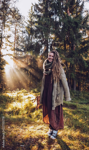 Young woman with dreadlocks in autumn fall forest in the morning sunshine