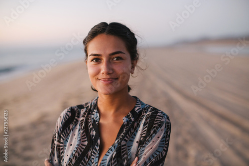 Content young woman looking at camera on the beach at sunset