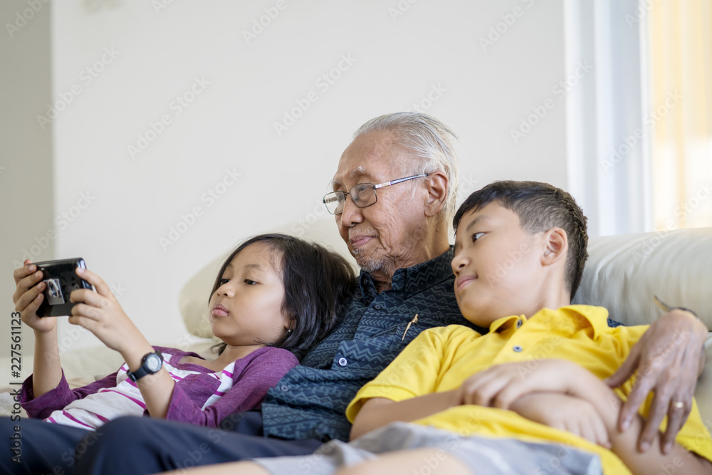 Old man and grandchildren relaxing on sofa