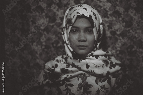 Young fashionable muslim girl in floral pattern hijab on flower prints shirt and ditsy background photo