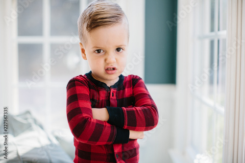 Adorable young boy in a plaid pajamas pouting photo