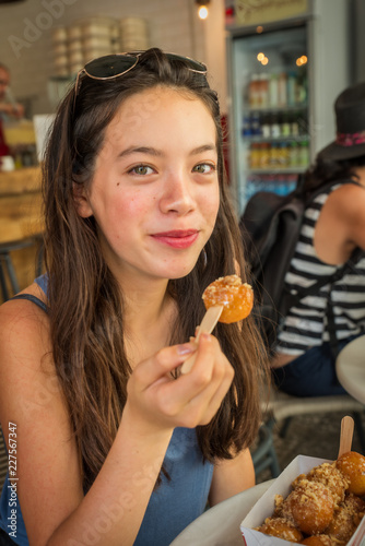 Teen eating lukamades  fried dough balls