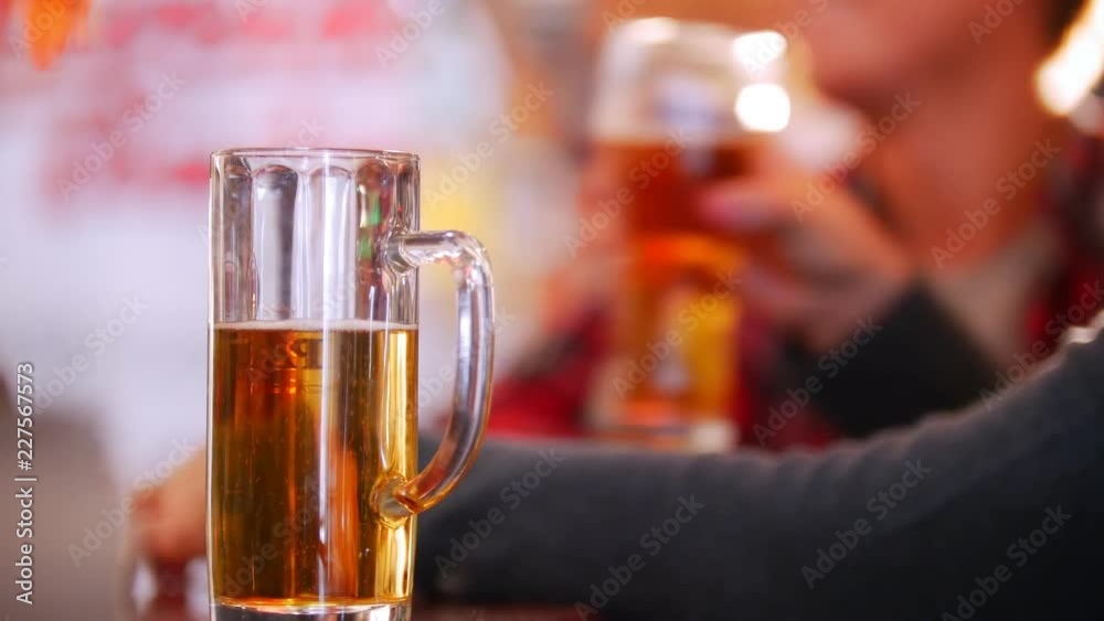Half empty pint of beer in focus. Talking guys at the background. Irish pub