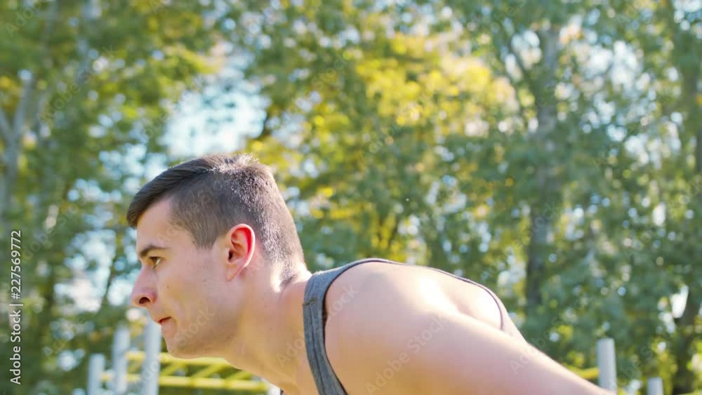 Male athlet does morning exercise outdoors close up slow motion. Workout standing on the is located near the lake with water and trees on the shore. Healthy lifestyle will power motivation concept Male athlet does morning exercise outdoors close up slow motion. Workout standing on the is located near the lake with water and trees on the shore. Healthy lifestyle will power motivation concept