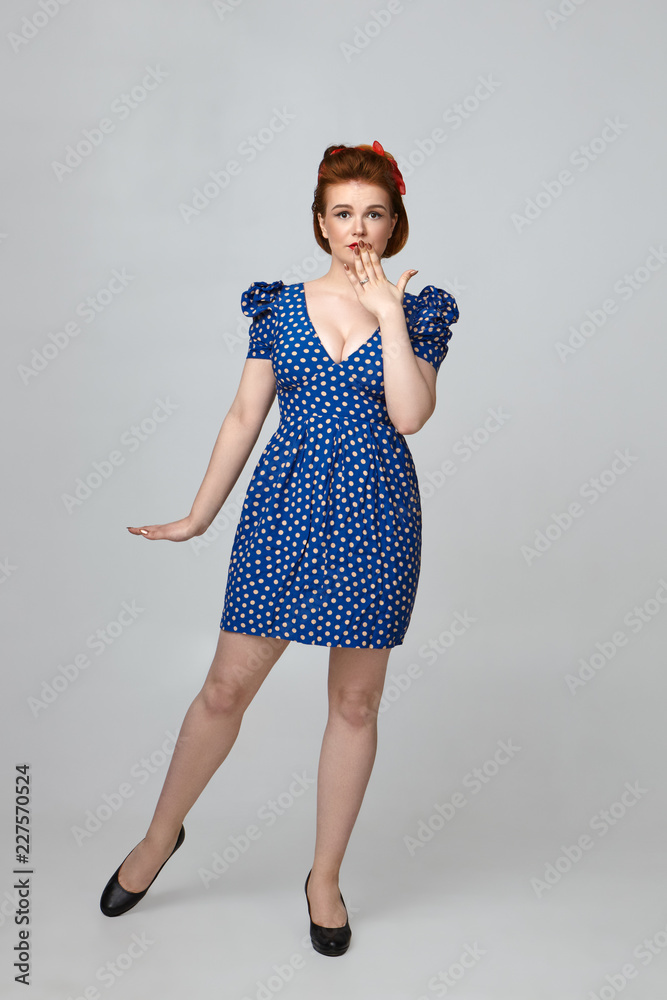 Omg. Astonished young beautiful housewife dressed in 60s retro outfit  having naive amazed look, covering mouth, being shocked with unexpected  news. Pin up girl in vintage dress expressing shock foto de Stock |