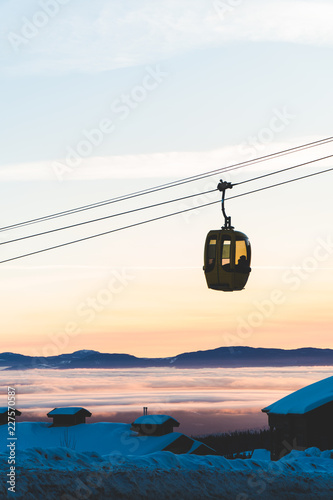 A gondola passing in front of a winter sunset