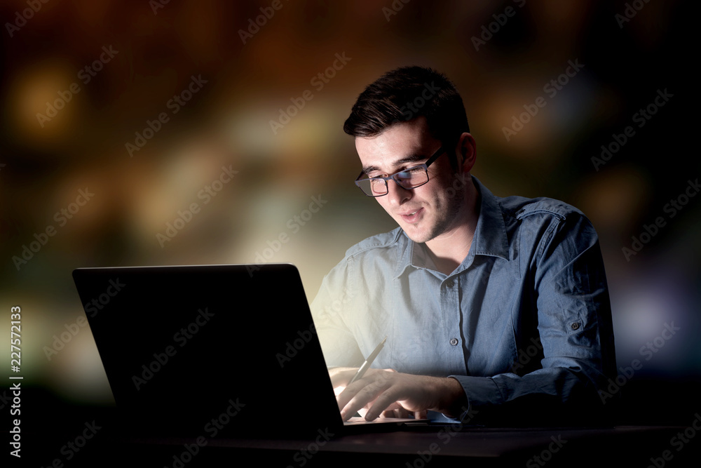 Young handsome businessman working late at night in the office Young handsome businessman working late at night in the office