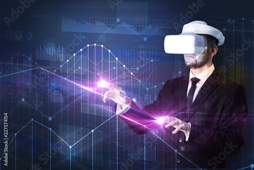 Businessman with virtual reality goggles organizing 3D graphs charts and financial variables 