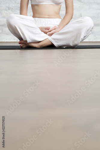 Young woman in the white outfit practicing stretching yoga positions, wellbeing and self care concept