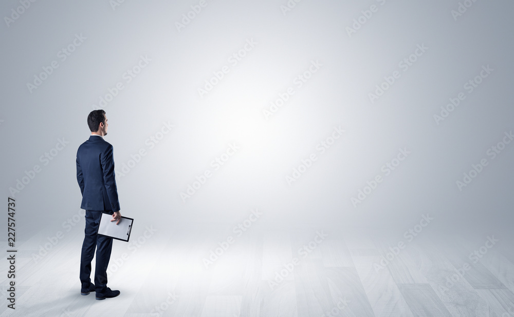 Man standing with his back in an empty room with object in his hand