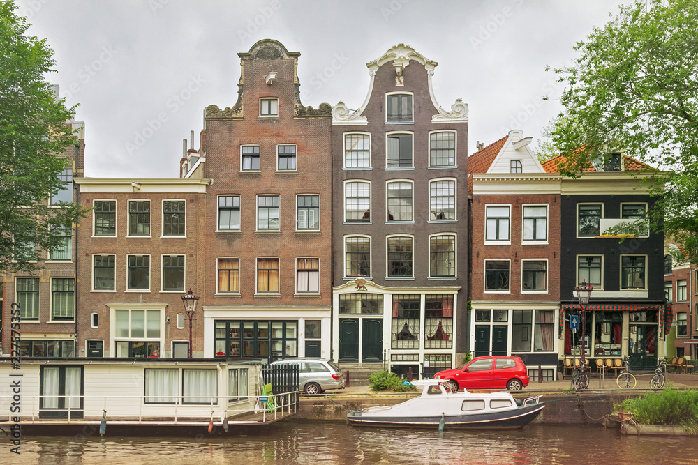 Fototapeta premium Old buildings near the one of the water canals in the historical part of Amsterdam, Netherlands.