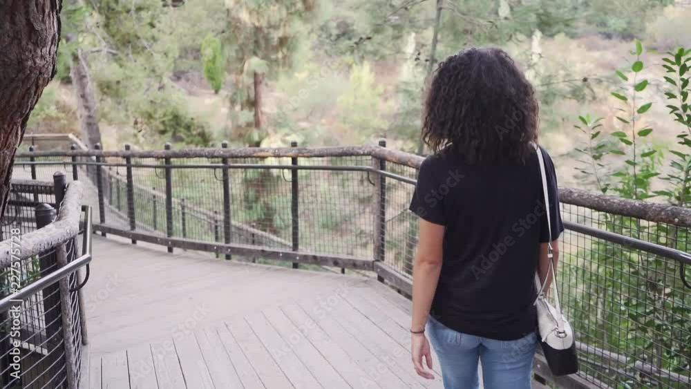 Young attractive millinial woman walking on a bridge path at the San Diego Zoo Safari Park