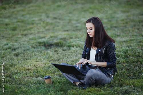 Young business woman sitting and working in park with laptop