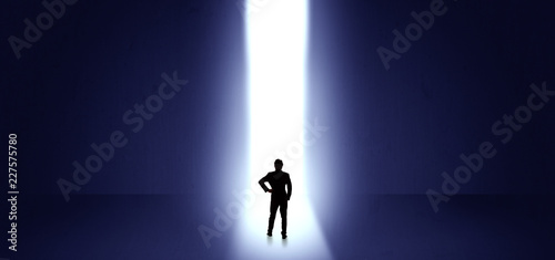 Businessman standing and seeing the light at the end of a big wall 