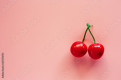 Fake red berries ornaments and decoration on pink background for Christmas day and holidays concept