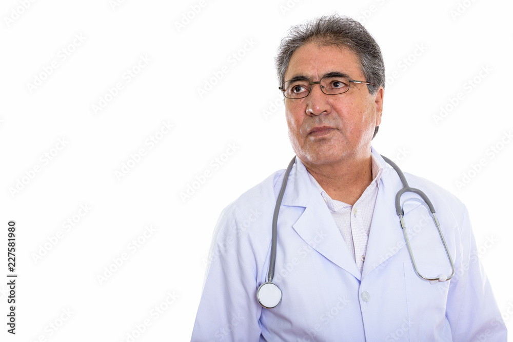 Studio shot of senior Persian man doctor thinking while looking Studio shot of senior Persian man doctor thinking while looking