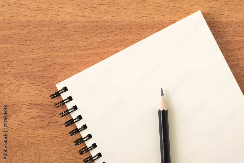 Top view of open spiral blank notebook with pencil on wood desk background Top view of open spiral blank notebook with pencil on wood desk background