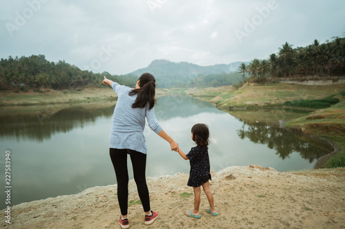 a mother and his daughter on the edge of the lake, hands pointin photo